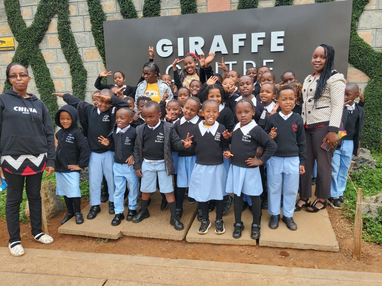 Pupils in school uniform posing outside the Giraffe Centre on a school trip
