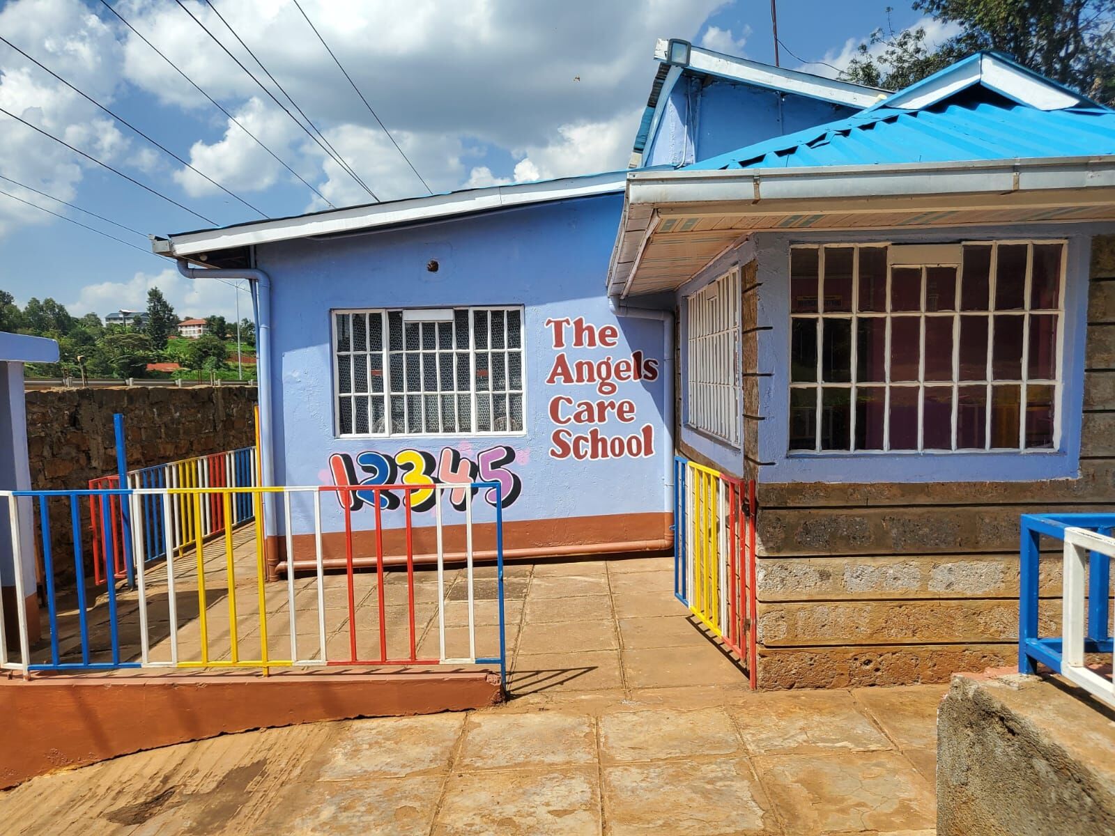 The school building with its blue roof, painted school name and colourful railings
