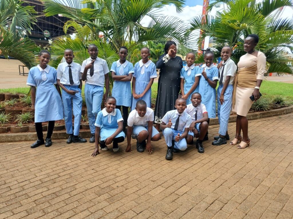 Older pupils in light-blue uniform with a teacher among palm trees on an outing