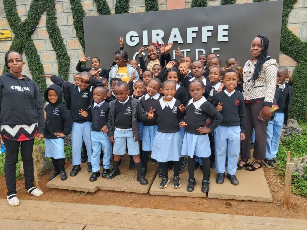 Pupils and teachers in school uniform posing outside the Giraffe Centre