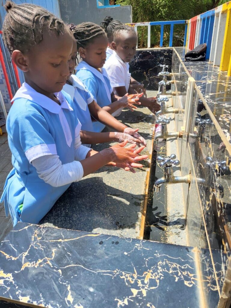 Pupils washing their hands with soap at a row of taps