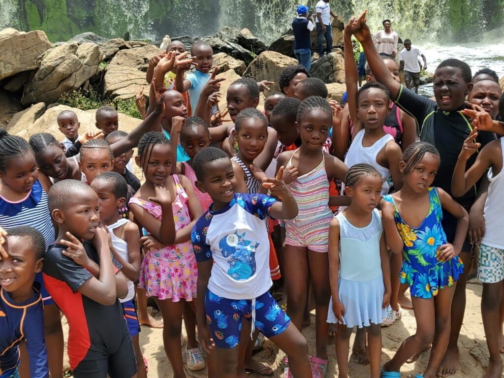 Pupils and teachers gathered at the rocks by a waterfall