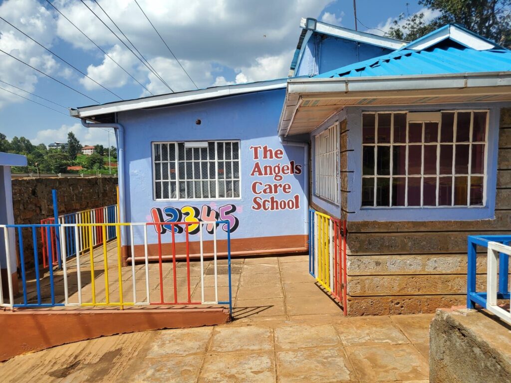 The school building with its blue roof, painted school name and colourful railings