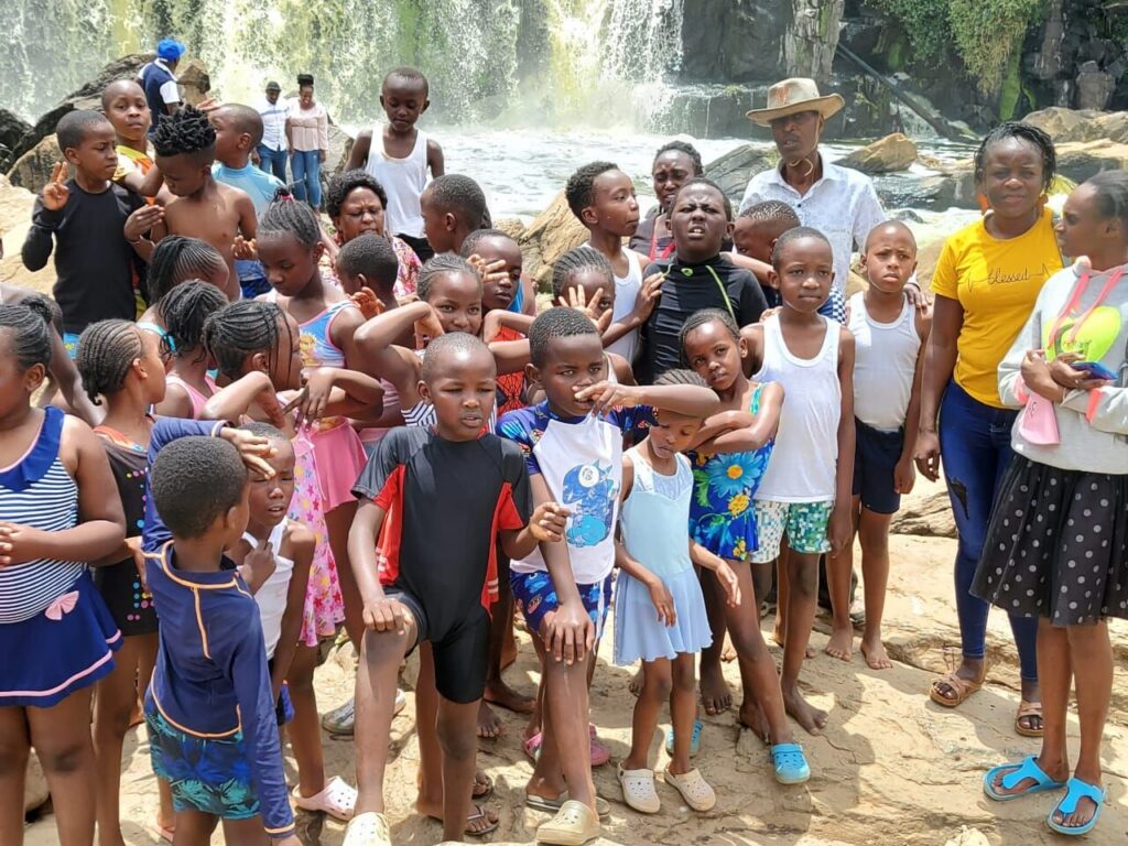 Pupils and teachers on a swimming trip beside a waterfall